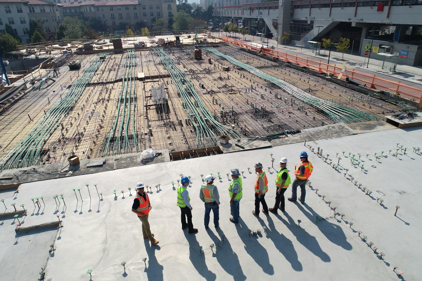 Construction crew in safety vests reviewing a slab pour